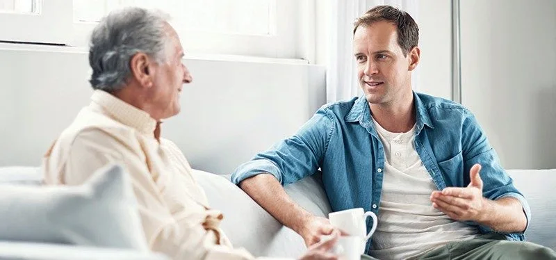 A son sharing a quiet moment with his father at home